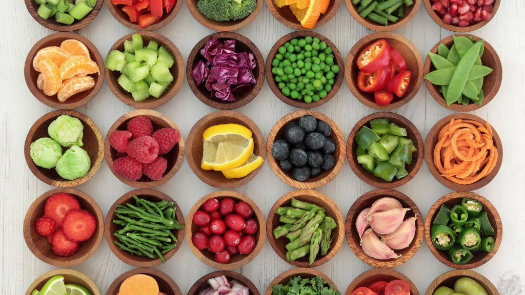 Pokrojone owoce i warzywa w drewnianych miseczkach.